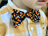 Tossed candy corn on black background, Halloween bow tie.